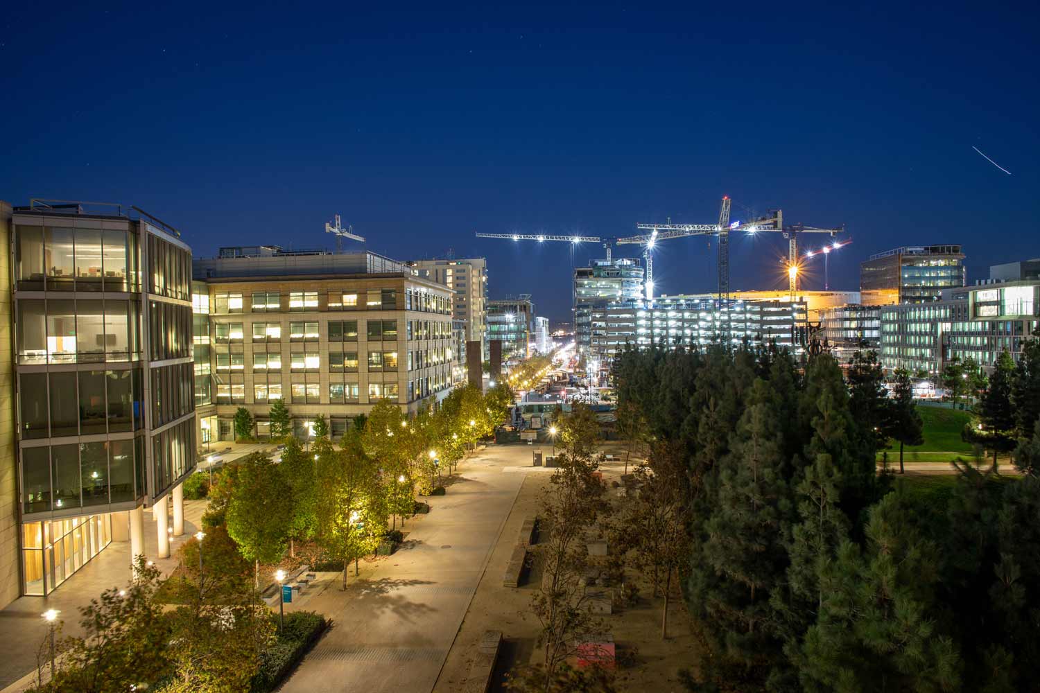 The buildings in Koret Quad illuminate with light among a evening night sky.
