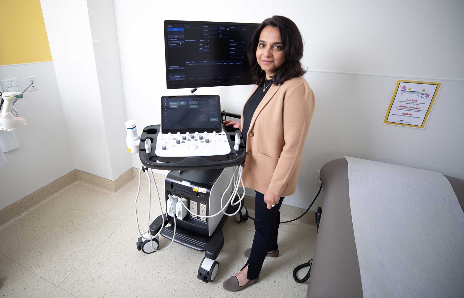 Dr. Sabina Ali stands next to a new machine used for intestinal ultrasounds.