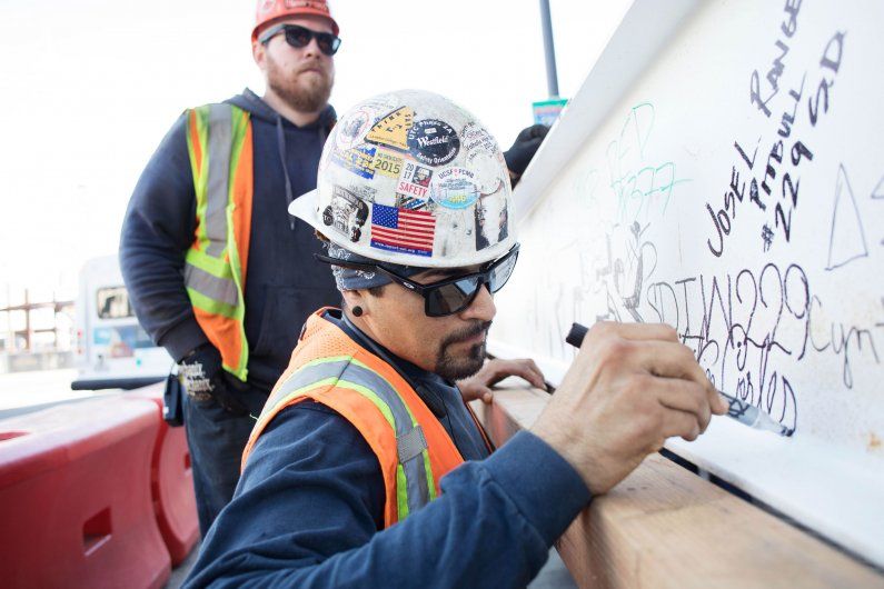 Construction site manager signing a beam.